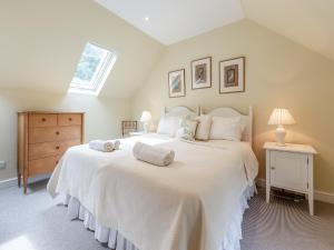 1 dormitorio con 1 cama blanca grande y ventana en The Coach House en Ingoldsby