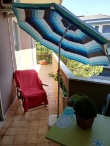 un parasol sur un balcon avec une chaise et une table dans l'établissement APPARTAMENTO STELLA MARINA, à Silvi Marina