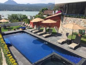 a swimming pool with chairs and umbrellas next to a building at Araucaria Hotel Boutique in Valle de Bravo