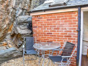 a table and chairs in front of a brick wall at Tyn Y Berth in Talsarnau