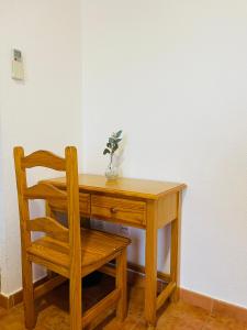 a wooden desk with a chair and a vase of flowers at Ballestar Hotel Bar & Grill in Barajas de Melo