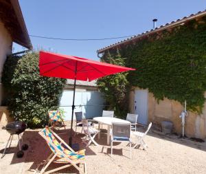a red umbrella and chairs and a table with a television at La Grange de Johanni in Davayé