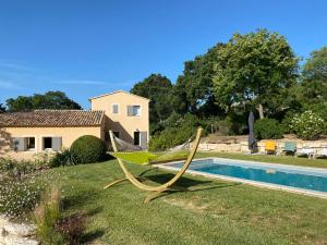 a hammock in a yard next to a swimming pool at Chante Coucou in Saint-Saturnin-lès-Apt
