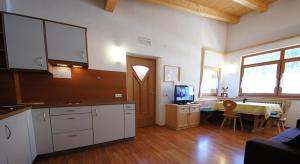 a kitchen with white cabinets and a table with a television at Apartments Antersi Silvia in San Vigilio Di Marebbe