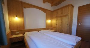 a bedroom with a white bed and wooden walls at Apartments Antersi Robbi in San Vigilio Di Marebbe