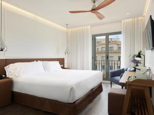 a bedroom with a large white bed and a desk at H10 Universitat in Barcelona +50 photos