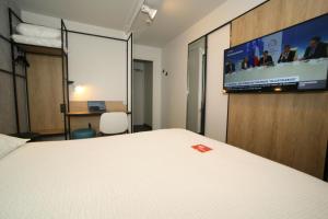 Cette chambre comprend un lit et une télévision à écran plat. dans l'établissement ibis Saint-Lô, à Saint Lo