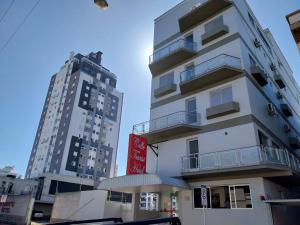 um edifício branco alto ao lado de dois edifícios altos em Colle Tourist Hotel em Criciúma