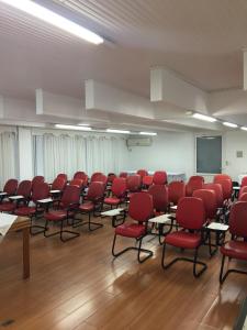 una sala de conferencias con sillas rojas y una pantalla en Colle Tourist Hotel, en Criciúma