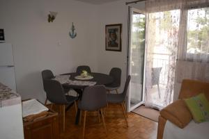 a dining room with a table and chairs and a window at Apartment Dragica in Kornić