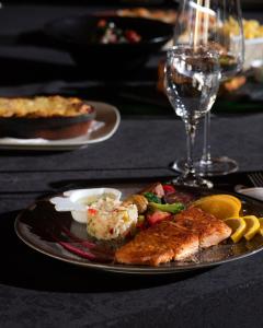 a plate with fish and vegetables and a glass of wine at Sunny Garden Pansion in Ulcinj +36 photos