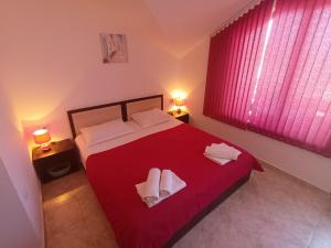 sypialnia z czerwonym łóżkiem i 2 ręcznikami w obiekcie Guest House Bа́kish Obzor w Obzorze