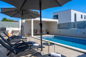 eine Terrasse mit Stühlen und Sonnenschirmen neben einem Pool in der Unterkunft Villa Ema and Ana in Pula