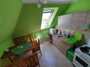 cocina con paredes verdes, mesa y fregadero en Dom Gościnny u Szymona, en Wrzosowo
