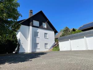 une maison blanche avec un toit noir et une allée. dans l'établissement Apartment Haus Aktiv Panorama, à Winterberg