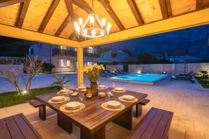 an outdoor dining area with a wooden table and a pool at Villa MarLea in Dubrovnik