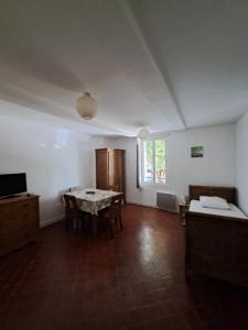 ein Wohnzimmer mit einem Tisch, Stühlen und einem Fenster in der Unterkunft Appart-Hôtel Résidence Maloc in Malaucène