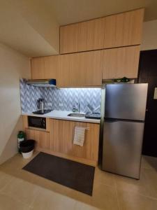 uma cozinha com um frigorífico de aço inoxidável e armários de madeira em Live the BGC lifestyle! em Manila