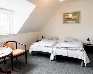 two beds in a room with a table and a chair at Abild Kro & Hotel in Tønder