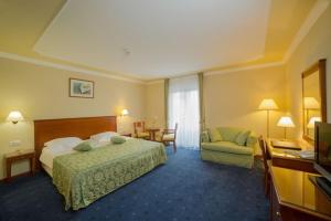 um quarto de hotel com uma cama e uma cadeira em Amadria Park Grand Hotel 4 Opatijska Cvijeta em Opatija