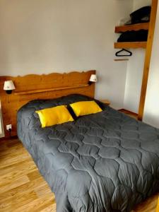 1 dormitorio con 1 cama con 2 almohadas amarillas en V du Bachat Arolles A12 - Appt 6 pers en Chamrousse