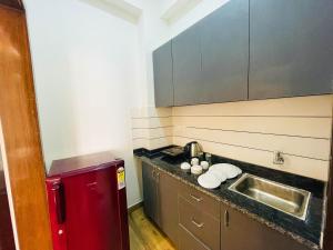 a small kitchen with a sink and a red refrigerator at The Empire Suites in Gurgaon