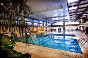 a large swimming pool in a building with a palm tree at Crowne Plaza Beijing Sun Palace by IHG in Beijing