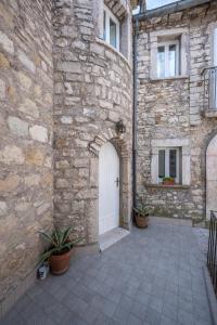 ein Steingebäude mit einer weißen Tür und einigen Pflanzen in der Unterkunft La torretta sul cortile in Monteroduni