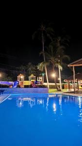 a large blue swimming pool at night with palm trees at Pousada Vila Cajuína - Luís Correia in Luis Correia