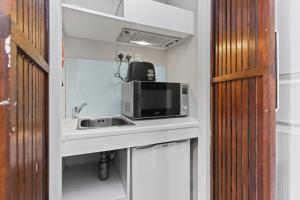 une cuisine avec évier et four micro-ondes sur un comptoir dans l'établissement Self-contained studio, à Londres