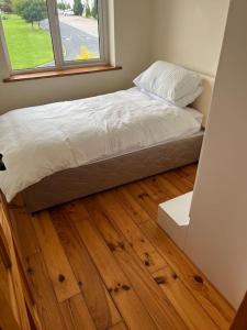 a bedroom with a bed and a wooden floor at Modern 4 Bed House in town in Tobercurry