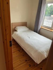 a small bed in a room with a window at Modern 4 Bed House in town in Tobercurry