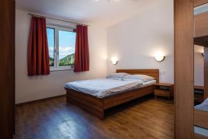 1 dormitorio con 1 cama y una ventana con cortinas rojas en VILA Stella, en Bystrá