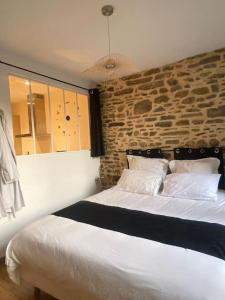 1 dormitorio con cama blanca y pared de ladrillo en Charmant logement avec jacuzzi, en Fougères