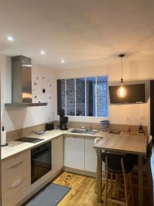 a kitchen with white cabinets and a table with chairs at Charmant logement avec jacuzzi in Fougères