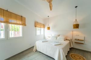 a white bedroom with a bed and two windows at Calas De Meca in Los Caños de Meca