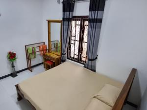 a small bedroom with a bed and a window at Nilaveli Guest House in Nilaveli