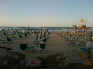 a beach with chairs and tables and the ocean at Hotel Vela Velo Club Vieste in Vieste