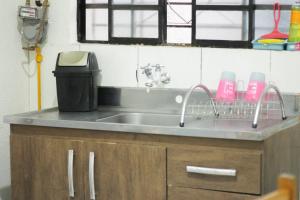 a kitchen counter with a sink and a trash can at Apartamento Inteiro Central 2 Quartos e Kitnet Inteira 01 quarto in Ponta Grossa
