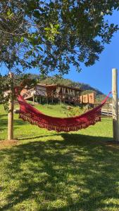 a hammock hanging from a tree in a field at Cabana Dois Amores. Destino romântico. in Barracão