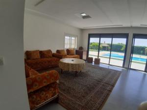 un soggiorno con divano, tavolo e piscina di Magnifique villa avec piscine a Kenitra