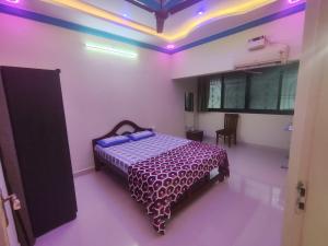 een slaapkamer met een bed in een kamer met paarse verlichting bij Serene Homestay in Panaji