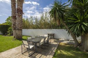a patio with a table and chairs and palm trees at Envie de Vivre in Agde