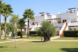 un grand bâtiment blanc avec des palmiers dans un parc dans l'établissement Great Appartement & Golf With Big Roof Terrace, à Alhama de Murcia