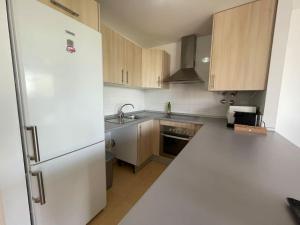 La cuisine est équipée d'un réfrigérateur blanc et de placards en bois. dans l'établissement Great Appartement & Golf With Big Roof Terrace, à Alhama de Murcia