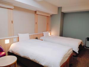 Dormy Inn Express Matsue في ماتسو: غرفة فندقية بسريرين وطاولة