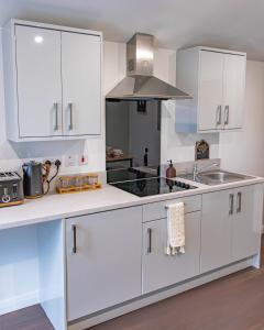 a kitchen with white cabinets and a stove top oven at Lough Beg Glamping in New Ferry