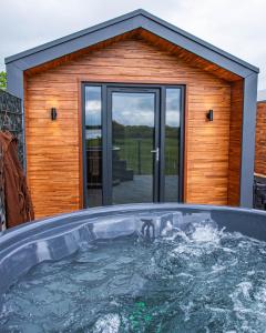 a hot tub in front of a house at Lough Beg Glamping in New Ferry