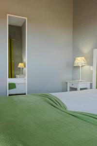 a bedroom with a bed with a green blanket at Quinta dos I's - Algarve in Algoz