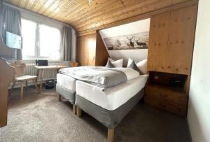 a bedroom with a bed and a desk and a window at Hotel Zartenbach B&B in Hinterzarten